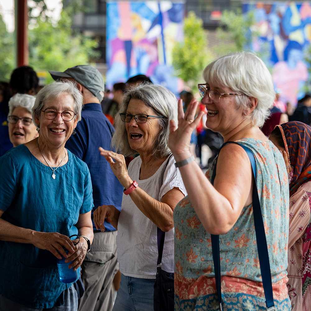 A group of volunteers and community members talking and laughing together at an outdoor community event